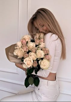 a woman is holding a bouquet of flowers in her hands and posing for the camera