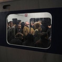 a group of people standing next to each other on a subway train, looking out the window