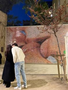 two people standing in front of a wall with a painting on it's side