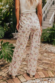 - Let your free spirit shine with these trendy pants! - Unlined material with a pink and yellow hued floral print - A high waistline with a functional drawstring, a hidden zip fly, and button closure - Functional side pockets, low cargo pockets, as well as optional back pockets that can be unstitched for functional use - A relaxed silhouette that ends in straight hemlines Floral Print High-waisted Pants For Day Out, Spring Cargo Pants With Elastic Waistband, Casual Beige Floral Print Bottoms, Beige Floral Print Pants For Spring, Spring Beige Floral Print Pants, Spring Floral Print Beige Pants, Beige Cotton Bottoms With Floral Print, High Waist Floral Print Bottoms For Day Out, Cream Floral Print Bottoms For Spring