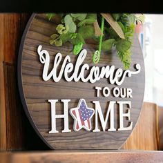 a wooden sign that says welcome to our home with an american flag on the front