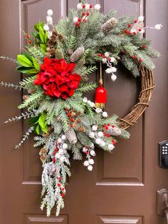 a wreath with poinsettis, pine cones and berries hangs on the front door