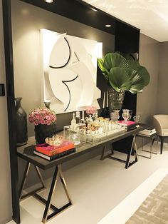 a table with vases and glasses on it in front of a large art piece