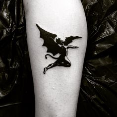 a black and white photo of a dragon tattoo on the leg