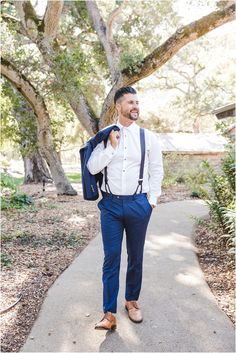 a man in a white shirt and blue pants is walking down the sidewalk with a backpack on his back