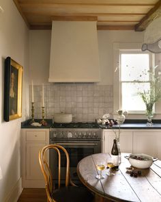 a kitchen with a table and chairs next to an oven in the middle of it