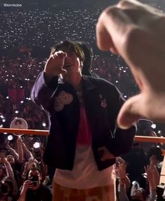 a man standing in front of a crowd holding his hand up