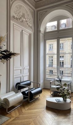 a living room filled with furniture next to large windows and lots of wood flooring