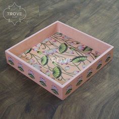 a pink box sitting on top of a wooden table with flowers painted on the inside