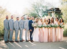 a group of people standing next to each other in front of some trees and bushes