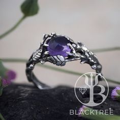 a close up of a ring on a rock with flowers in the background and leaves around it