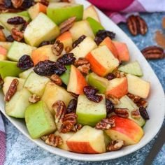 a white bowl filled with apples and pecans on top of a blue table cloth