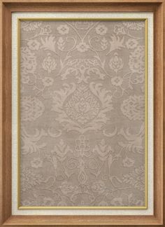 an ornate wall hanging in a wooden frame with a beige and white pattern on it