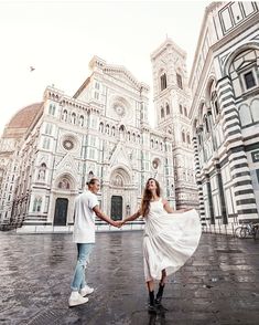 two people holding hands in front of a large building