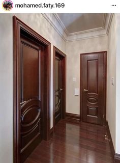 an empty hallway with two wooden doors and hard wood flooring on the other side