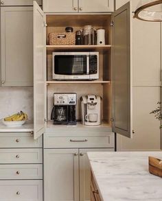 an open cabinet in a kitchen filled with lots of counter top space and white cabinets