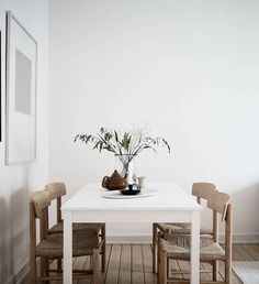 a white table with four chairs and a vase filled with flowers sitting on top of it