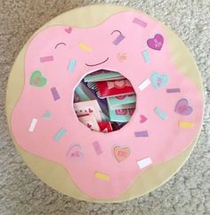 a pink doughnut with sprinkles and hearts on it sitting on the floor