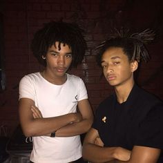 two young men standing next to each other with dreadlocks on their head and arms