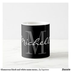 a black and white coffee mug with the letter m in cursive writing on it