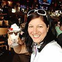 a woman wearing headphones and smiling at the camera with her dog in front of her