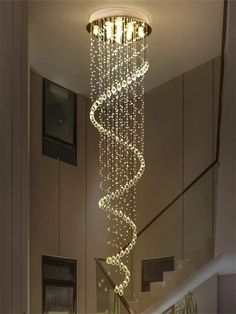 a spiral chandelier hanging from the ceiling in a house with stairs and windows