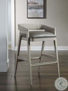 a gray stool sitting on top of a hard wood floor next to a white wall