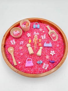 a wooden bowl filled with lots of pink stuff and toy items on top of it