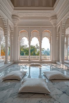 the floor is covered in white marble and has four pillows on it, as well as large windows