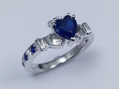 Claddagh Heart Blue Sapphire and diamonds Ring In 14K White Gold, Irish Celtic Band Center Stone: Shape: Heart Shape Carat Weight: Approx. 0.96 Color, Clarity: Medium Blue, Eye Clean Measurements: Approx. 6 x 6mm Side Stones Shape: Round Cut Diamonds & Sapphires Color, Clarity: G-H, VS-SI 100% natural diamonds & Medum Blue, Eye Clean (sapphires) Carat Weight: 0.10ct + 0.06 = 0.16ct Setting Metal: 14K White Gold Ring Size: 6.25; Free sizing from 4-8 Return Policy: 100% satisfaction guaran Blue Sapphire Diamond Ring With Heart Cut, Blue Diamond Heart Ring For Wedding, Blue Heart Cut Sapphire Ring For Formal Events, Blue Heart Cut Sapphire Ring For Formal Occasions, Blue Heart Cut Ring With Brilliant Cut, Valentine's Day Blue Diamond Ring, Heart Shaped Sapphire Rings For Formal Occasions, Blue Diamond Heart Cut Rings, Formal Sapphire Heart-shaped Rings