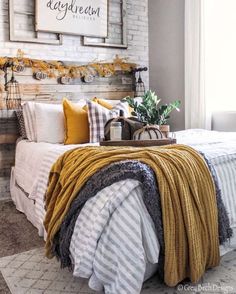 a bed with blankets and pillows on top of it next to a brick wall in a bedroom