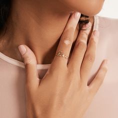 a woman wearing a gold ring with the word love on it