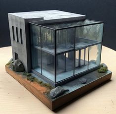 a model of a house made out of concrete and glass sitting on top of a wooden table