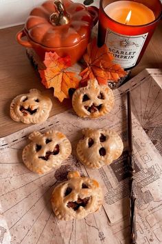 four small pies on a table next to a candle and an orange pumpkin jar