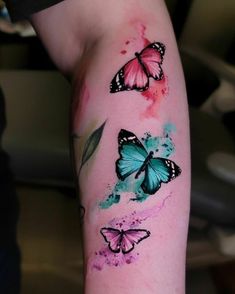 a woman's arm with three butterflies painted on it and watercolor paint splatters