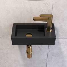 a black sink with gold faucet on the wall