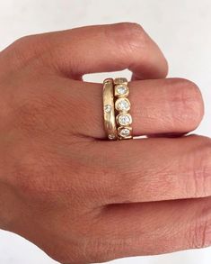 a person's hand with a gold ring and three diamond stones on the band