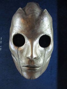 an alien mask with two black eyes and one white face is shown in front of a blue background