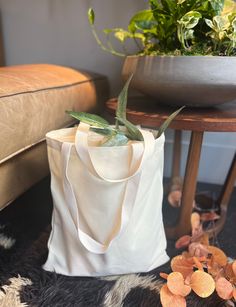 a white bag sitting on top of a rug next to a table with potted plants