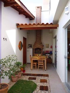 an outdoor kitchen and dining area with potted plants on the floor, next to a patio