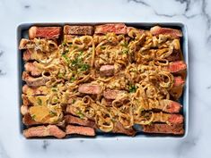 meat and noodles in a casserole dish on a marble table