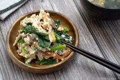 a wooden bowl filled with food next to chopsticks on top of a table