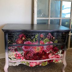 an old dresser with flowers painted on the front and sides, sitting in a room next to a window