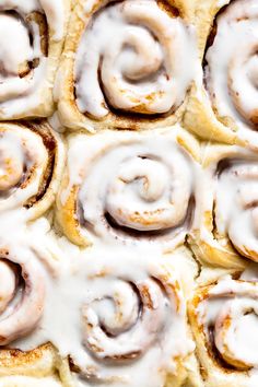 cinnamon rolls with icing sitting on top of each other in a baking pan, ready to be baked