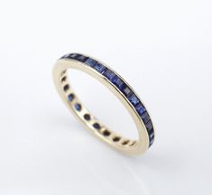 a yellow gold ring with blue sapphires on the sides and dots in the middle