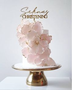 a white cake with pink flowers on top sitting on a gold plated platter