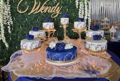 a blue and white wedding cake sitting on top of a table next to other cakes