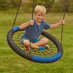 a young boy is sitting on a tire swing