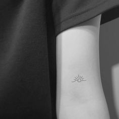 a woman's arm with a small sun tattoo on the left side of her arm