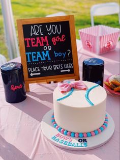 a baseball themed cake sits on a table with cupcakes and other items around it